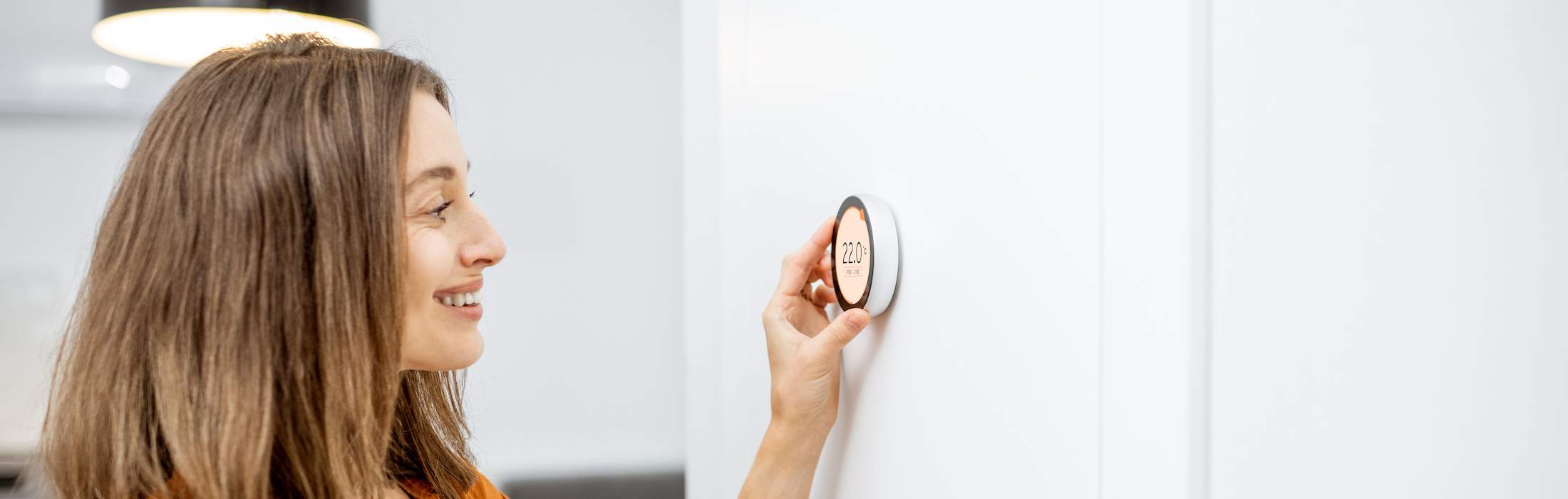 Heating Control - Young woman regulating heating temperature